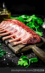 Raw rack of lamb with parsley and oil. On a black background. High quality photo. Raw rack of lamb with parsley and oil.