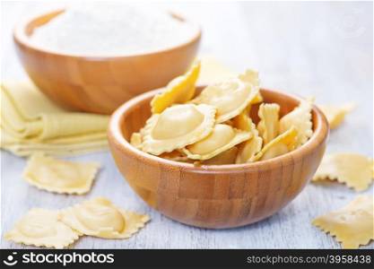 raw ravioli and flour in the bowl and on a table