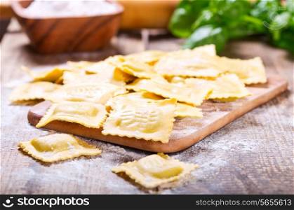 Raw ravioli with flour on wooden table
