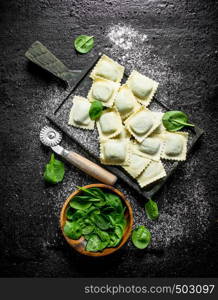 Raw Ravioli with spinach. On black rustic background. Raw Ravioli with spinach.