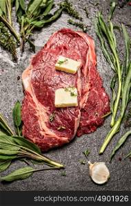 Raw ribeye steak with fresh herbs variety and butter, ingrediets for cooking, top view