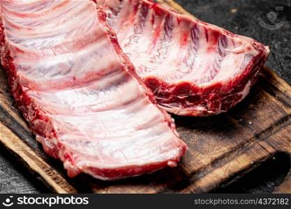 Raw ribs on a cutting board. On a black background. High quality photo. Raw ribs on a cutting board.