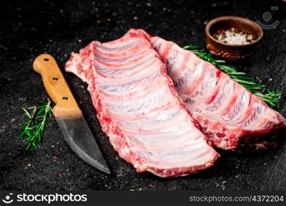 Raw ribs on a cutting board. On a black background. High quality photo. Raw ribs on a cutting board.