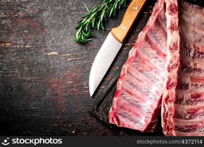 Raw ribs on a cutting board. On a rustic background. High quality photo. Raw ribs on a cutting board.