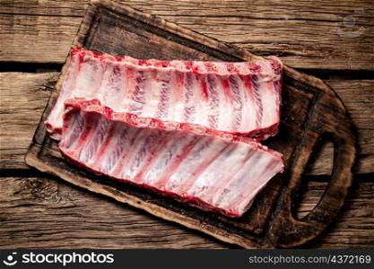Raw ribs on a wooden cutting board. On a wooden background. High quality photo. Raw ribs on a wooden cutting board.