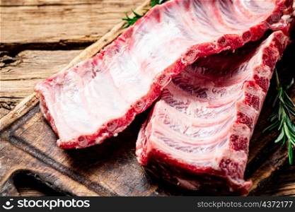 Raw ribs on a wooden cutting board. On a wooden background. High quality photo. Raw ribs on a wooden cutting board.