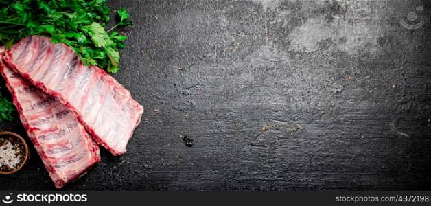Raw ribs with herbs and spices. On a black background. High quality photo. Raw ribs with herbs and spices.