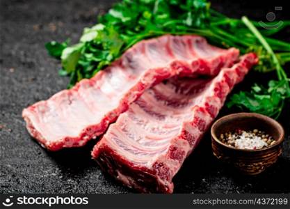 Raw ribs with herbs and spices. On a black background. High quality photo. Raw ribs with herbs and spices.