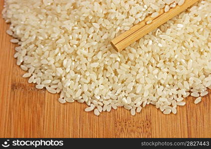 raw rice and chopsticks on bamboo board