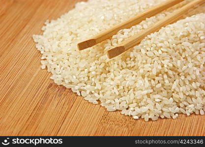 raw rice and chopsticks on bamboo board