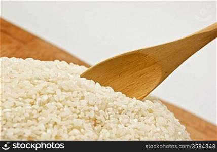 raw rice and wooden spoon on bamboo board