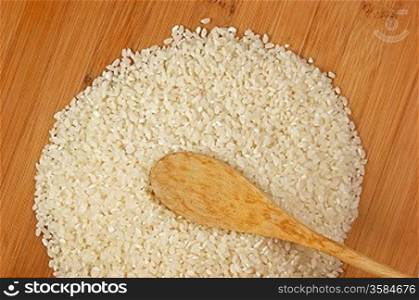 raw rice and wooden spoon on bamboo board