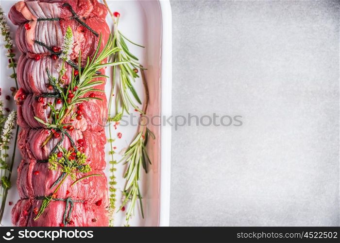 Raw roast beef tied with a rope , cooking preparation with herbs and spices, top view, place for text