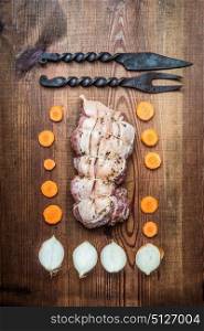 Raw roast pork preparation on rustic wooden background with cooking strings and kitchen tools, top view, flat lay
