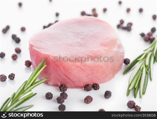 Raw round pork steak slices with pepper and rosemarine on white background