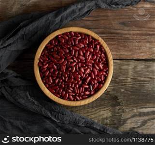raw round red beans in a plate on a wooden table. Organic meal. Vegetarian healthy natural food.