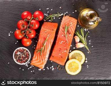 Raw salmon fillet and ingredients for cooking on a dark slate background. Top view, flat lay. Raw salmon fillet