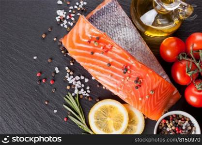 Raw salmon fillet and ingredients for cooking on a dark  slate background. Top view. Raw salmon fillet 