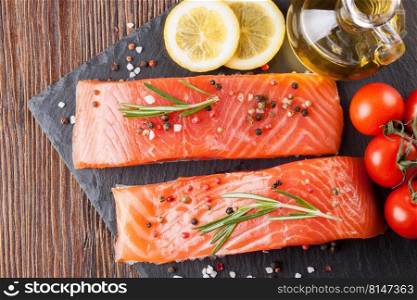 Raw salmon fillet and ingredients for cooking on a slade board and  brown wooden background. Top view. Raw salmon fillet with spices