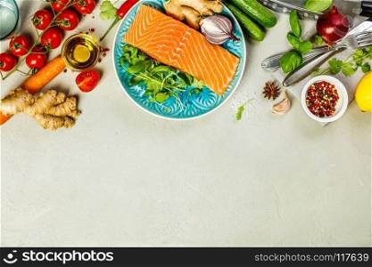Raw salmon fillet and ingredients for cooking on concrete background in a rustic style. Top view