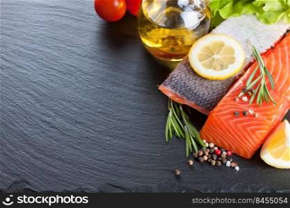 Raw salmon fillet, spices and vegetables on a dark slate background with copy space for text. Raw salmon fillet