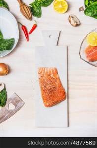 Raw Salmon fillets on white cutting board with healthy ingredients on kitchen table background, top view. Diet nutrition and healthy food concept