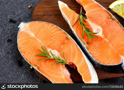 Raw salmon fish fillet and ice for cooked steak seafood / Fresh salmon steak with herbs and spices lemon rosemary on wooden cutting board background