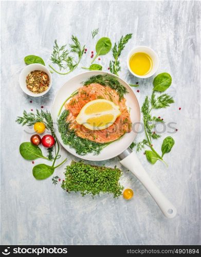 raw salmon in white pan with lemon and fresh herbs, top view