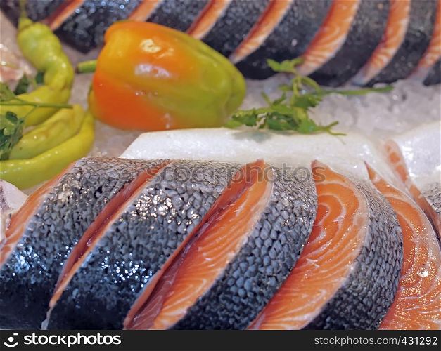 Raw salmon on ice at a fish market with vegetables
