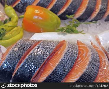 Raw salmon on ice at a fish market with vegetables