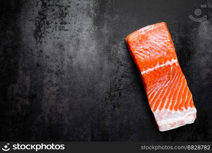 Raw salmon or trout sea fish fillet on black metal background, top view