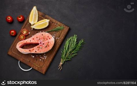 Raw salmon steak on a wooden cutting board, lemon slices, spices. Top view on black table. Copy space