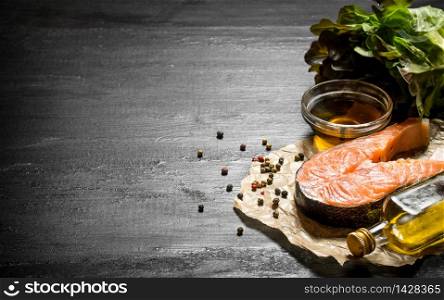 Raw salmon with olive oil, spices and herbs. On the black chalkboard.. Raw salmon with olive oil, spices and herbs.