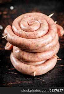 Raw sausage for frying on the table. Against a dark background. High quality photo. Raw sausage for frying on the table.
