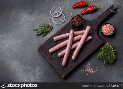 Raw sausages and ingredients for cooking. Top view with copy space on stone table. Raw sausages with spices on a wooden cutting board on a stone background with copy space for your text