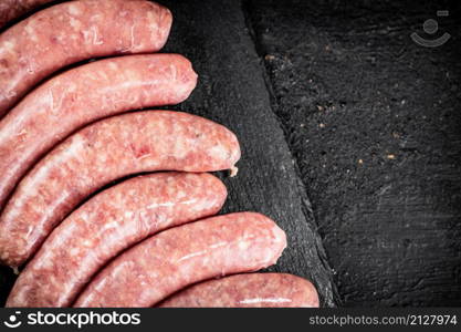 Raw sausages made of fresh meat on a stone board. On a black background. High quality photo. Raw sausages made of fresh meat on a stone board.