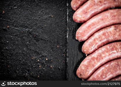 Raw sausages made of fresh meat on a stone board. On a black background. High quality photo. Raw sausages made of fresh meat on a stone board.