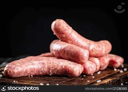Raw sausages on a cutting board. On a rustic dark background. High quality photo. Raw sausages on a cutting board.