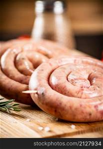 Raw sausages on a wooden background. High quality photo. Raw sausages on a wooden background.