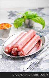 raw sausages on metal plate and on a table