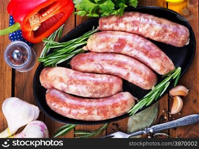 raw sausages on plate and on a table