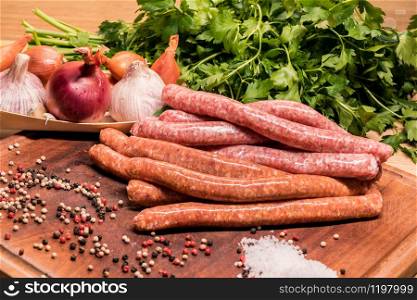 raw sausages with chilli and herbs on a wooden board with spices