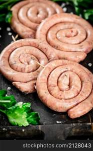 Raw sausages with parsley. On a black background. High quality photo. Raw sausages with parsley. On a black background.