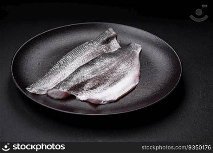 Raw sea bass fish fillet with salt, spices and herbs on a ceramic plate prepared for baking. Raw sea bass fish fillet with salt, spices and herbs on a ceramic plate