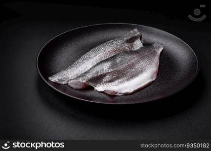 Raw sea bass fish fillet with salt, spices and herbs on a ceramic plate prepared for baking. Raw sea bass fish fillet with salt, spices and herbs on a ceramic plate
