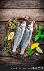raw sea bass fish on wooden background top view