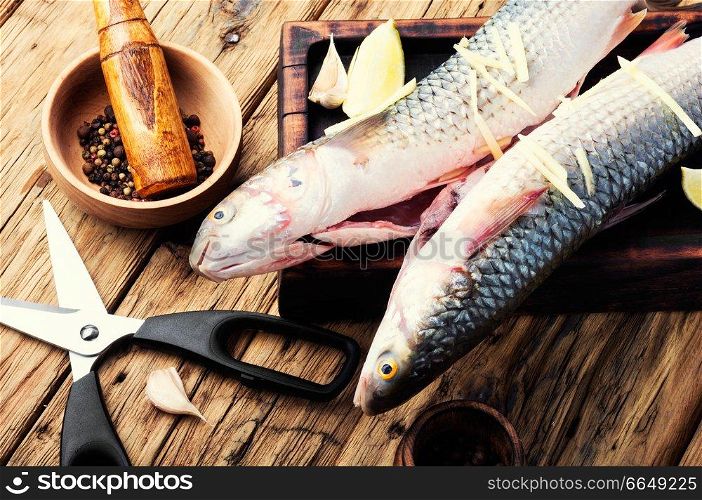 Raw sea fish on wooden kitchen board.Cooking concept.Seafood. Whole raw spiced fish