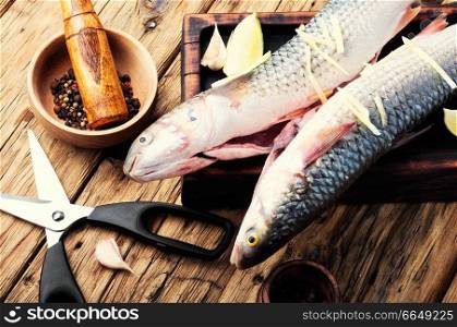 Raw sea fish on wooden kitchen board.Cooking concept.Seafood. Whole raw spiced fish