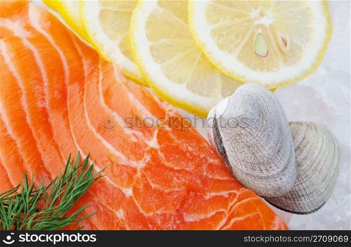 Raw seafood on a bed of crushed ice, garnished with slices of lemon and dill, ready for cooking.