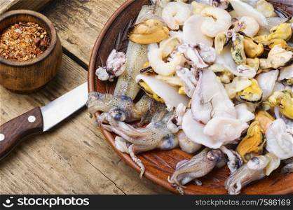 Raw seafood with fresh mussels,clams,squid, shrimps and spice. Raw seafood on a wooden board